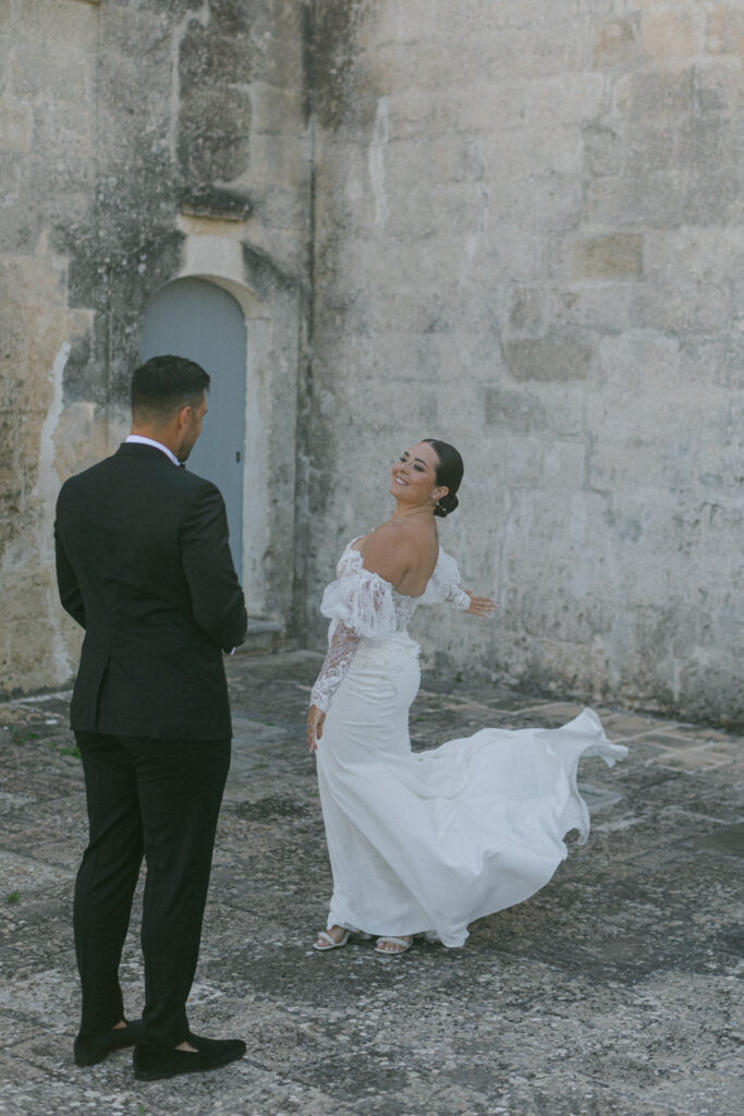 The essence of the Puglian wedding affair is captured in the bride's approach, her footsteps whispering across the stone, leading to a heart-stirring first look.