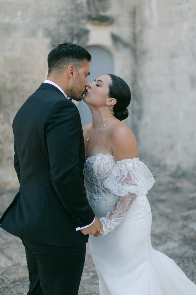 Encapsulating a traditional Puglian wedding affair, the couple shares a secluded moment of awe and affection during their first look, surrounded by ancient architecture