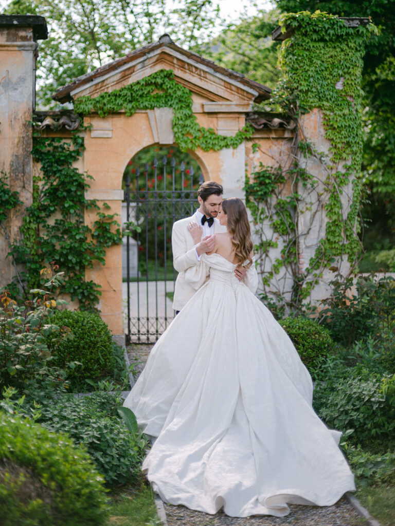 A couple shares a tender moment in the lush gardens of Villa Balbiano, epitomizing the romance of a Luxury Balbiano Wedding