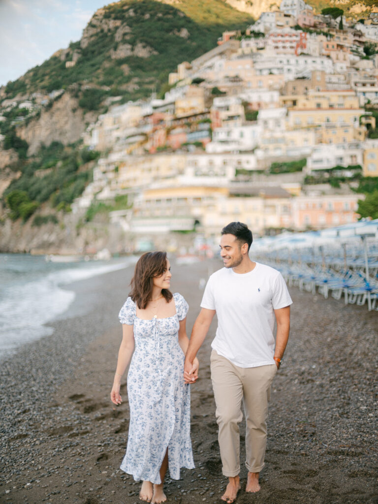 Honeymoon in Positano: A couple embraces on a sun-drenched terrace, with the colorful cliffs of Positano and the sparkling Mediterranean in the background.