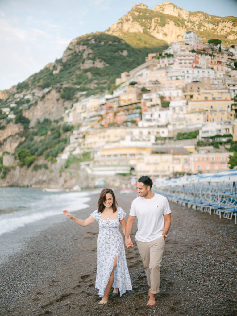 Honeymoon in Positano: A couple embraces on a sun-drenched terrace, with the colorful cliffs of Positano and the sparkling Mediterranean in the background.