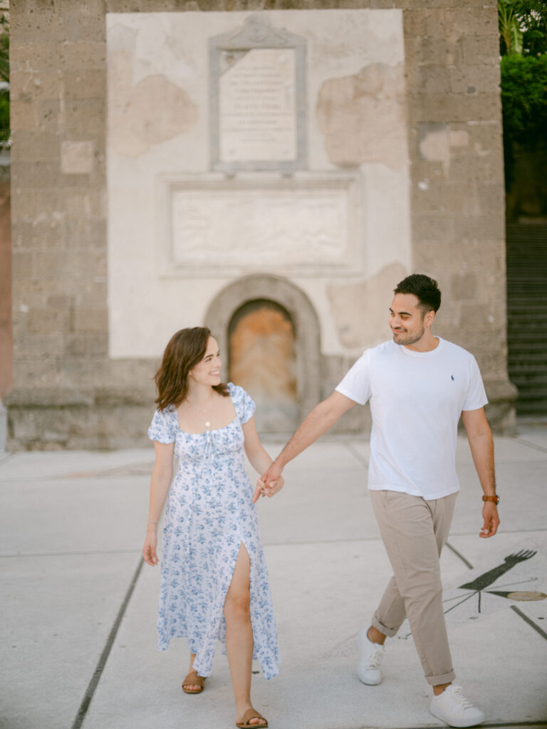 Romantic stroll through the charming streets during their honeymoon in Positano, with vibrant flowers cascading from the buildings.