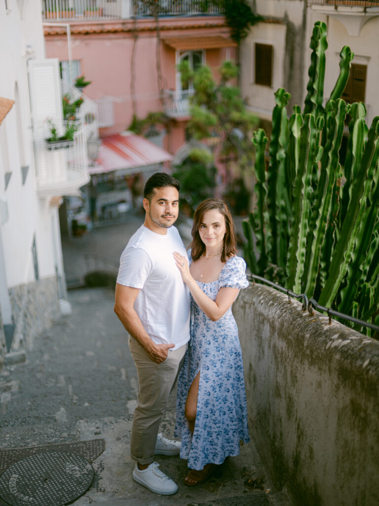 Romantic stroll through the charming streets during their honeymoon in Positano, with vibrant flowers cascading from the buildings.